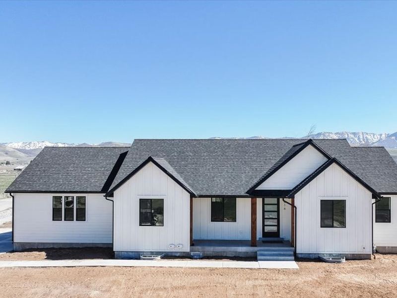 White single-level home with black gables and a covered porch, before landscaping