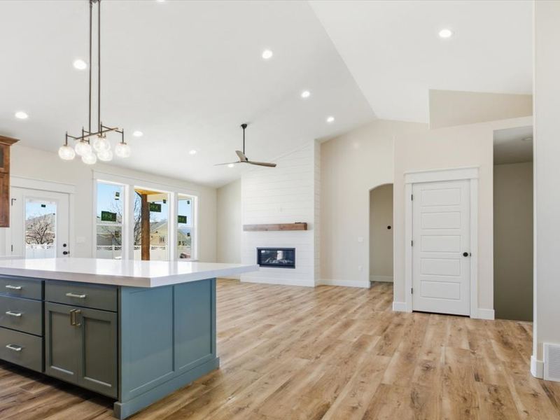 Open kitchen and great room with a teal island and vaulted ceiling