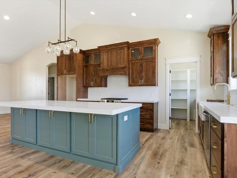 Kitchen with a teal island, stained upper cabinets, and quartz counters