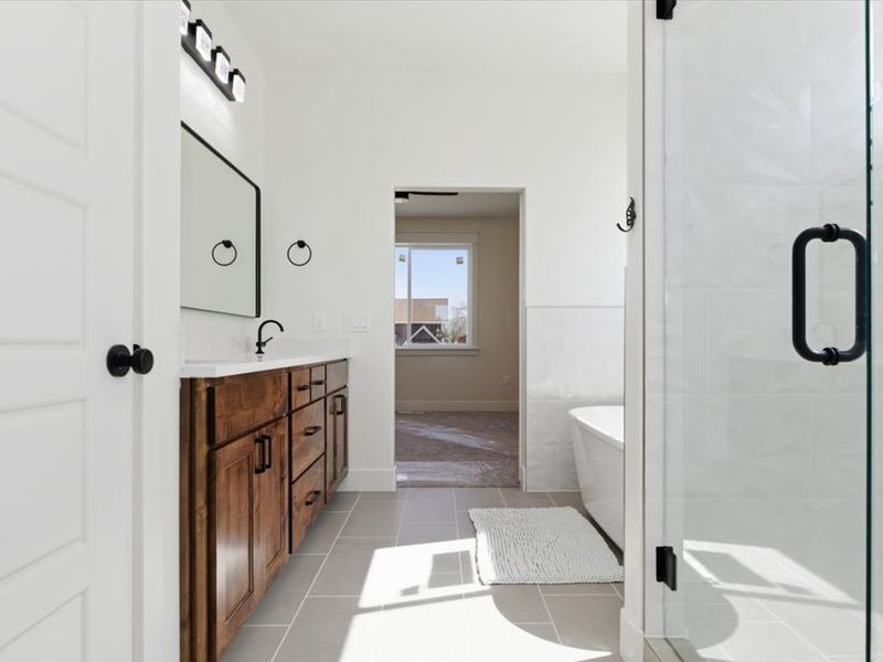 Primary bath with a glass shower, freestanding tub, and wood vanity