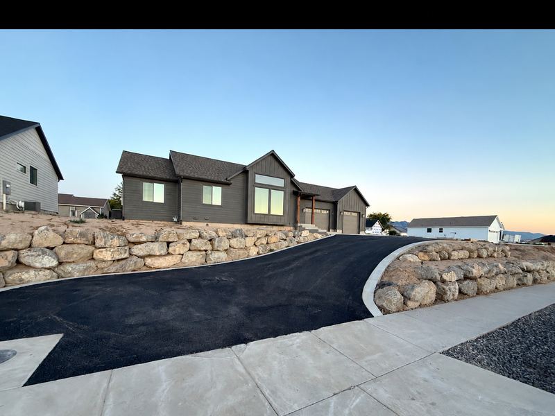 Curved driveway with boulder retaining walls on the hillside lot
