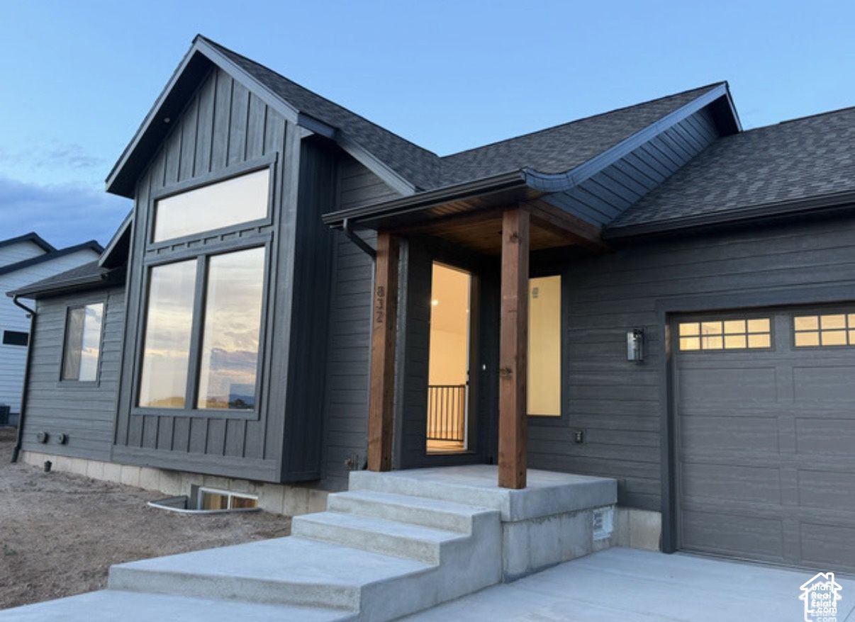 Front entry of 832 S 1100 E, Preston, Idaho, with dark board-and-batten siding, wood porch posts, and concrete steps