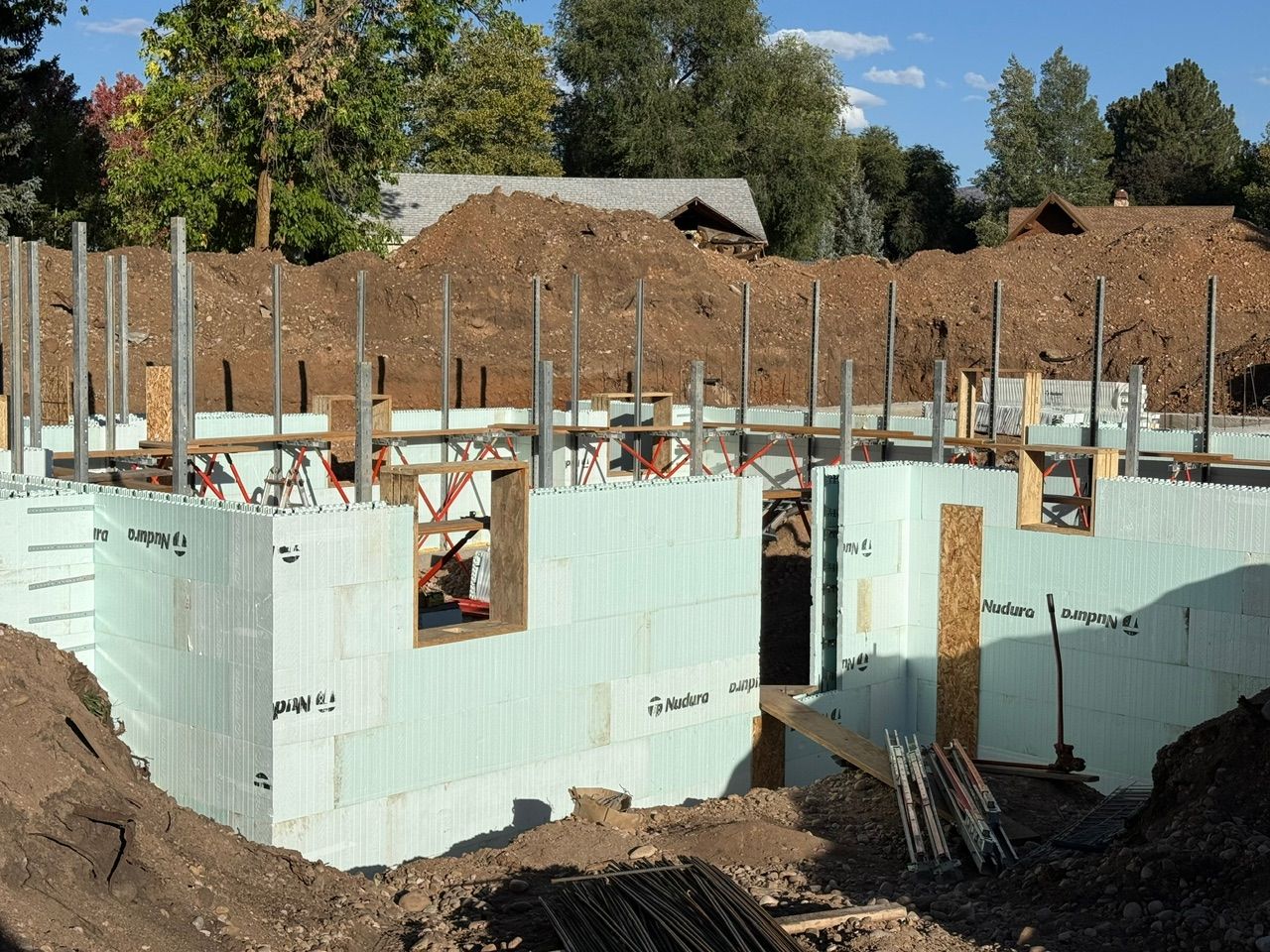 Green ICF foam block walls with vertical rebar and wood window bucks on a basement foundation